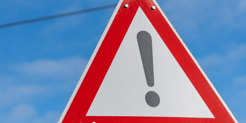 Triangular hazard sign displaying exclamation mark with a red outline