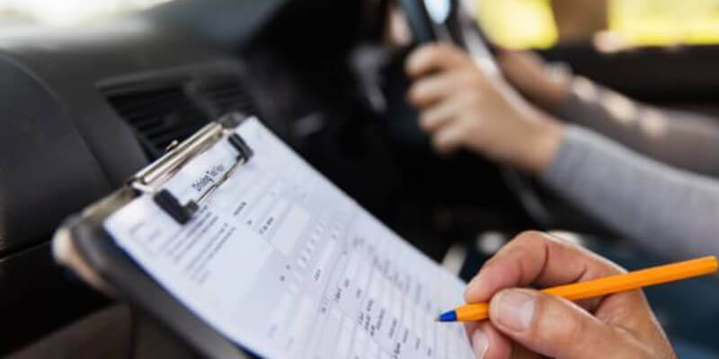Examiner marking the driving test sheet